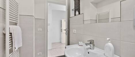 A modern bathroom with a white sink, a mirror, and a towel rack.