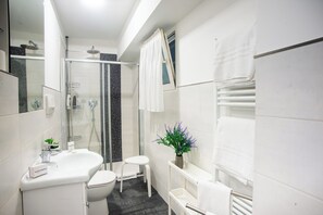 A modern bathroom with a glass-enclosed shower, a white sink, and a small stool. - Matteo's Flat (Sanremo)