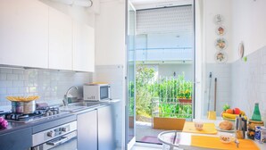 Une cuisine moderne avec un coin repas, un balcon agrémenté de plantes et une vue sur l’extérieur.
