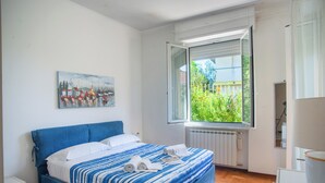 Une chambre à coucher avec un lit, une fenêtre donnant sur un paysage agréable, un radiateur et un tableau accroché au mur.