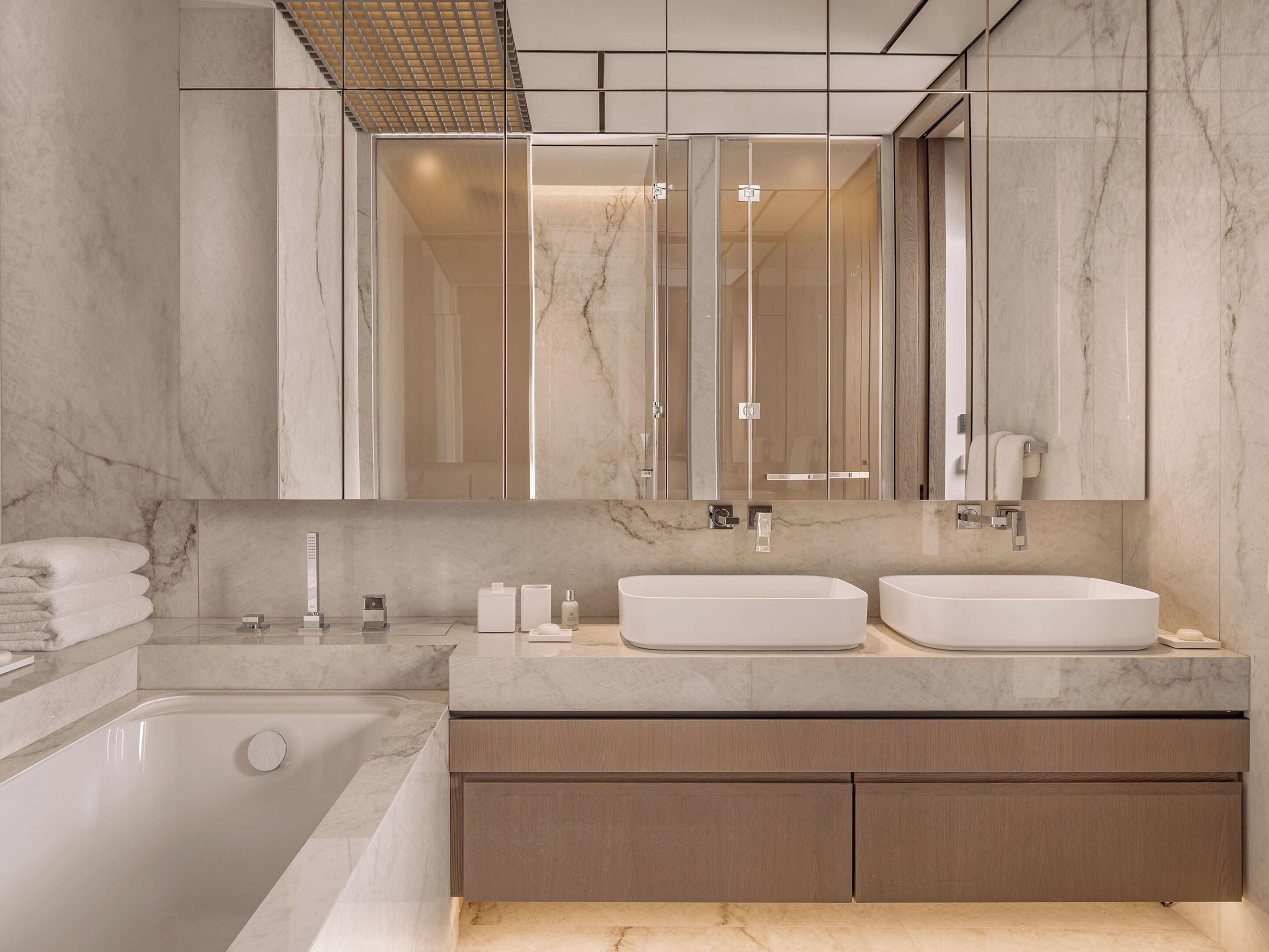 A modern bathroom with two sinks, a bathtub, and a large mirror.