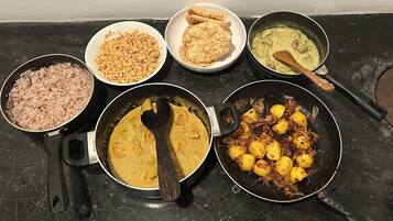 A kitchen counter with various dishes including rice, a curry, and fried items.
