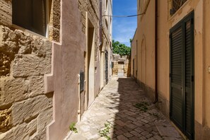 A narrow cobblestone alleyway between buildings with stone walls and wooden shutters. - 3936 Corte dei Falconi by Barbarhouse (Lecce)