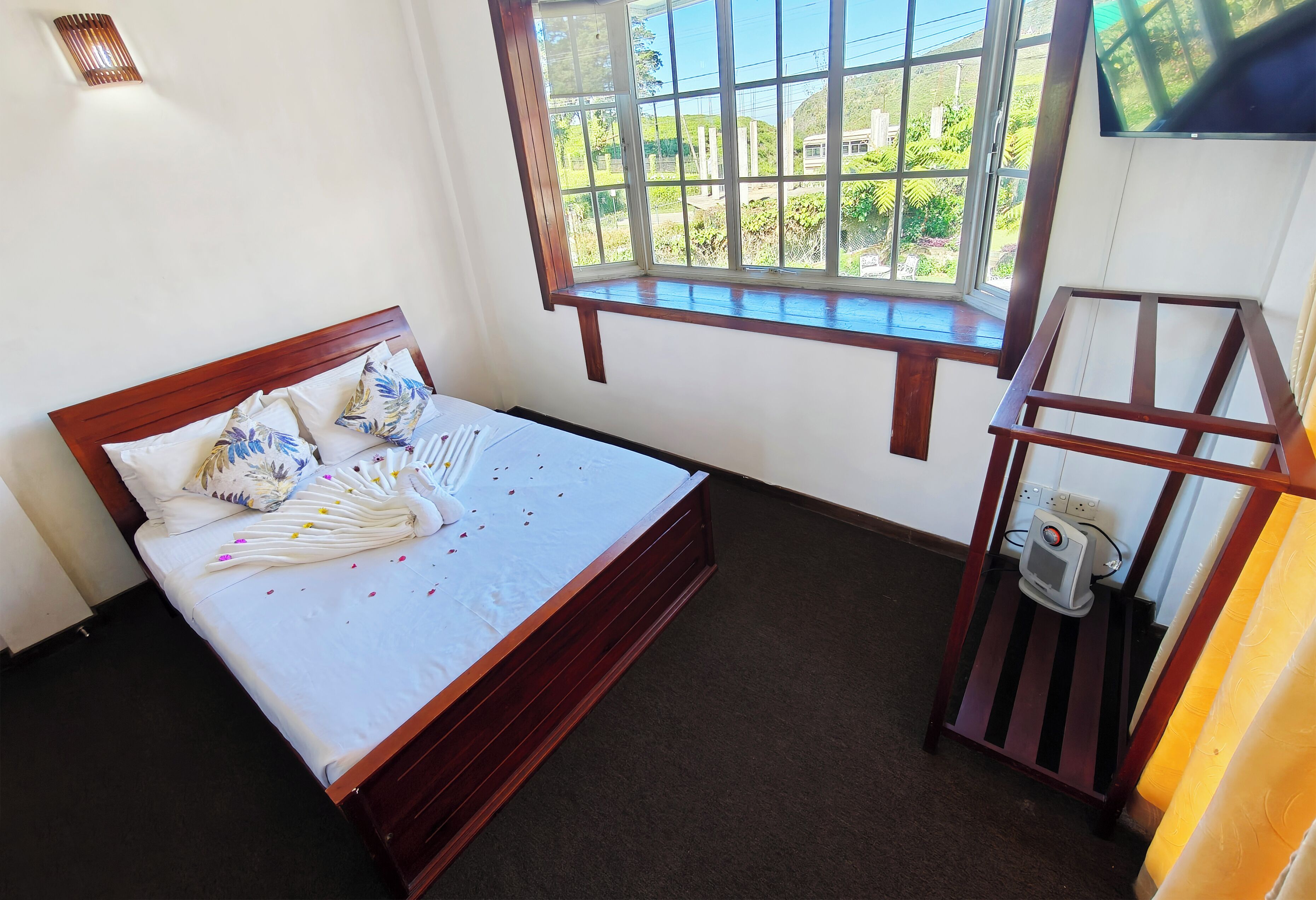 Une chambre avec un lit, une fenêtre donnant sur un beau paysage, une télévision et une petite table.