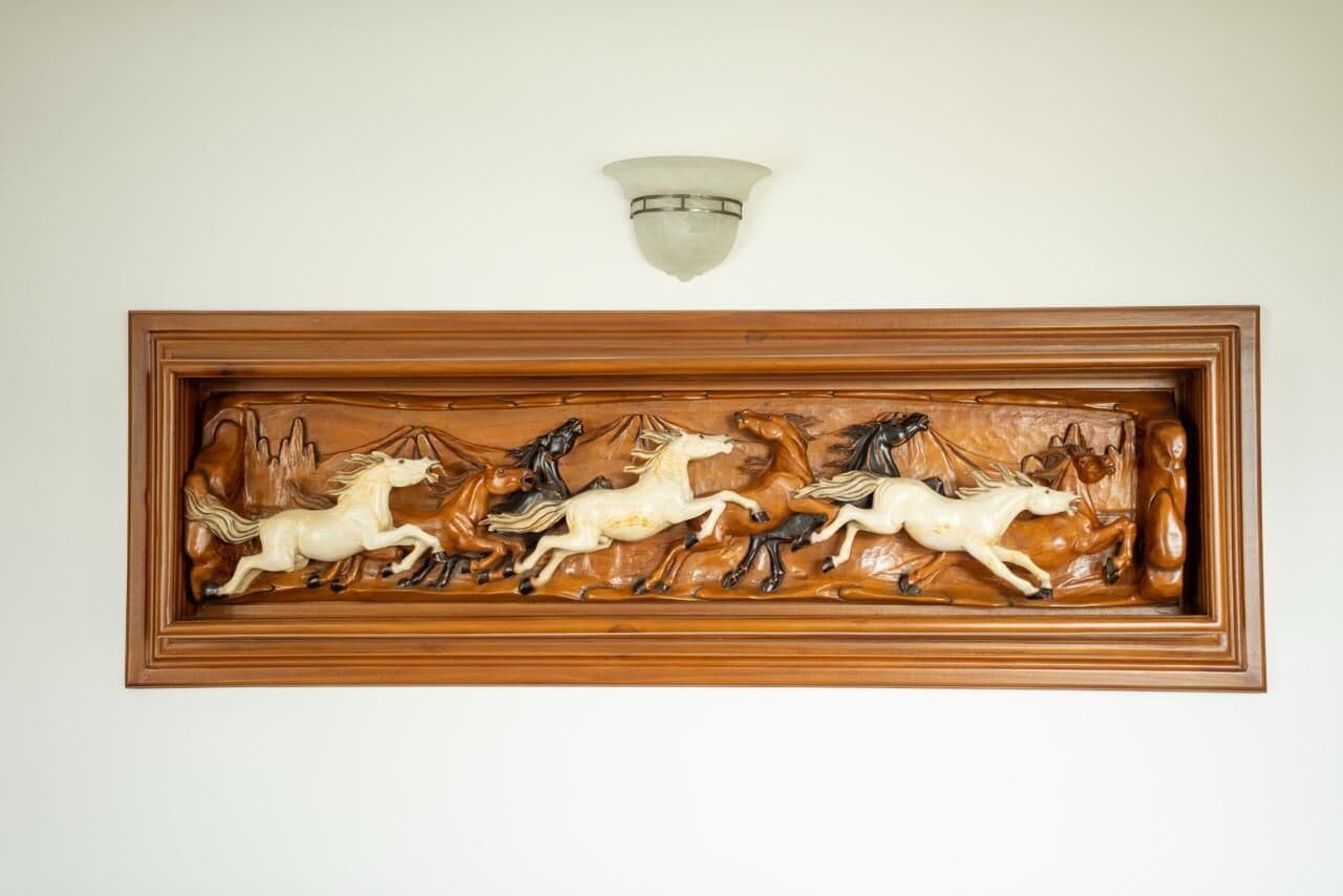 A wall-mounted wooden carving of horses.
