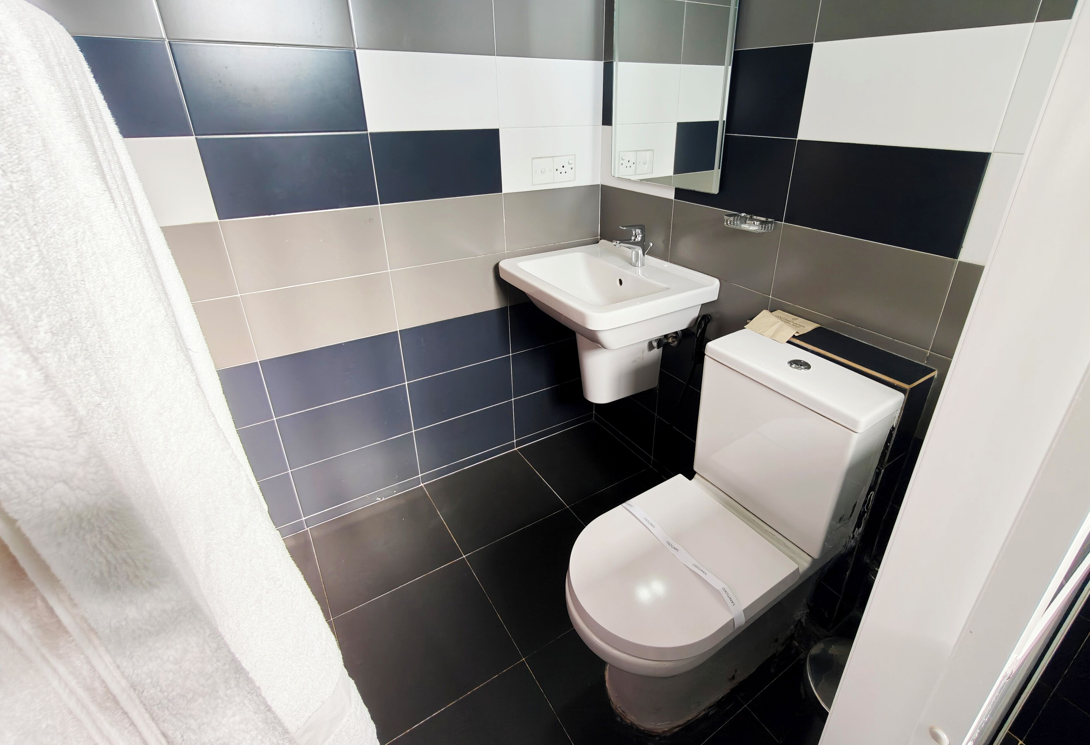 Un bagno con un water bianco, un lavandino e uno specchio.