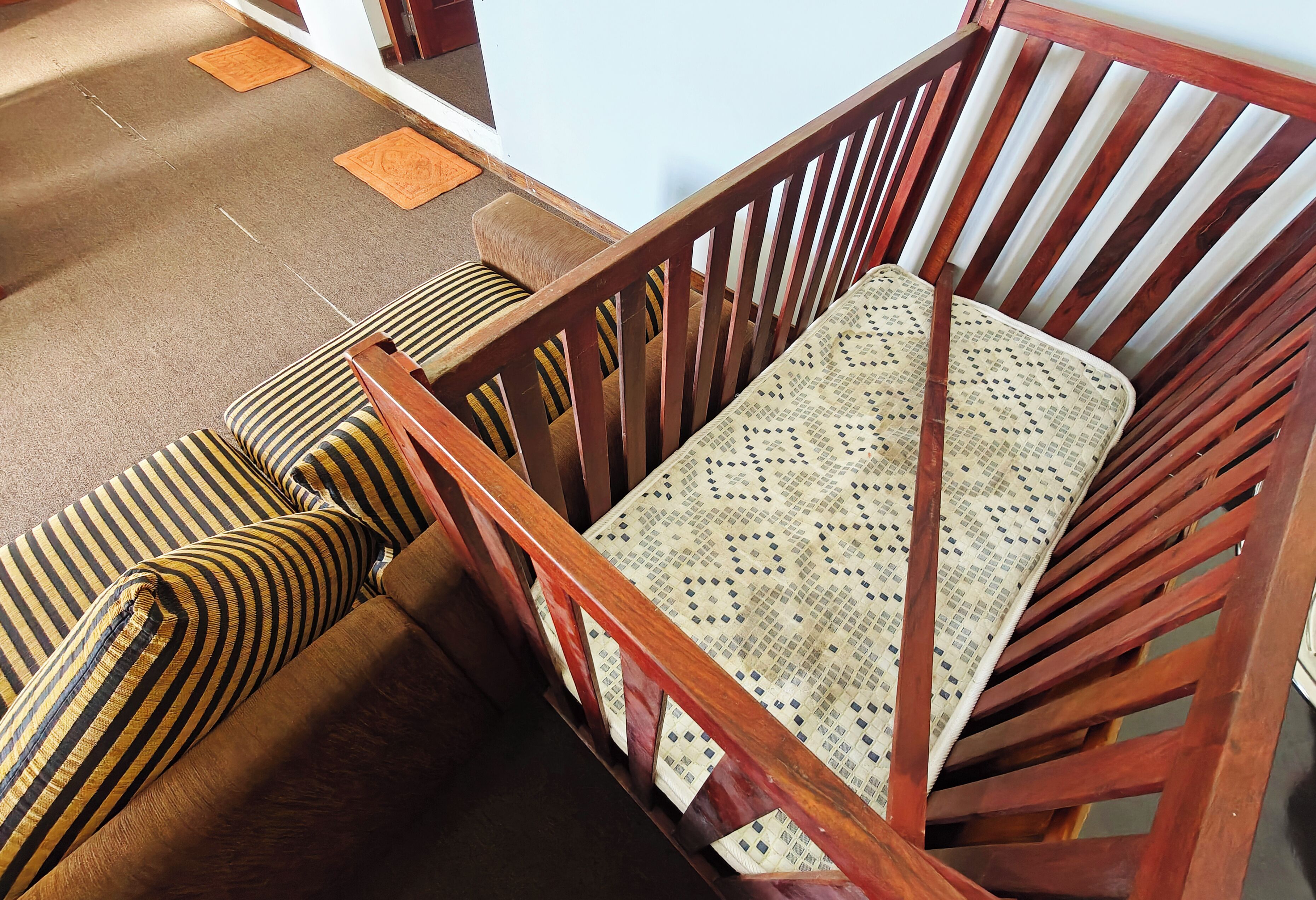 A wooden chair with a patterned cushion, a wooden bench with striped cushions, and a patterned tablecloth.
