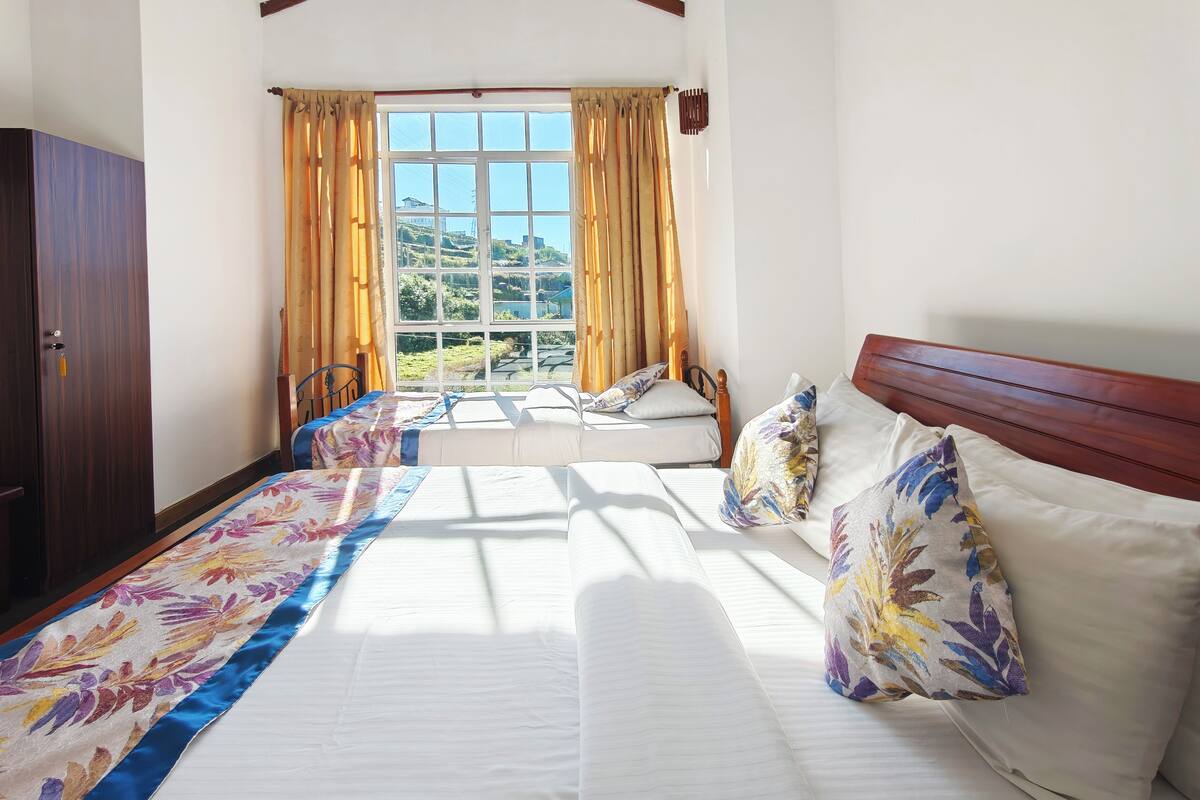 Un dormitorio con cama, ventana con cortinas, armario de madera y vista a un paisaje.