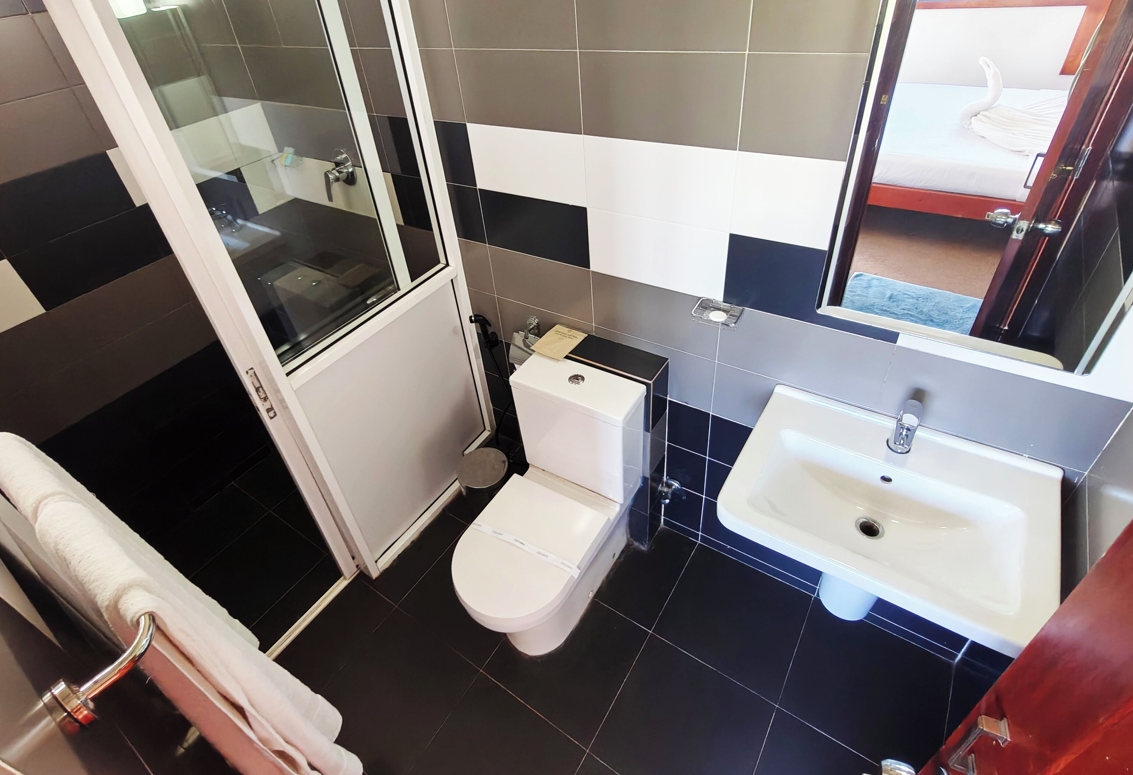 A bathroom with a toilet, sink, and glass shower enclosure.