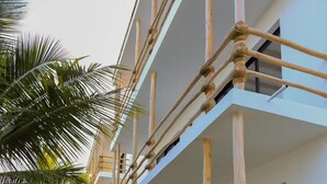 A modern building with a bamboo fence, a stone pathway, and lush greenery. - Ahadi Beachfront 2 Bedroom by YourHost (Mtwapa)