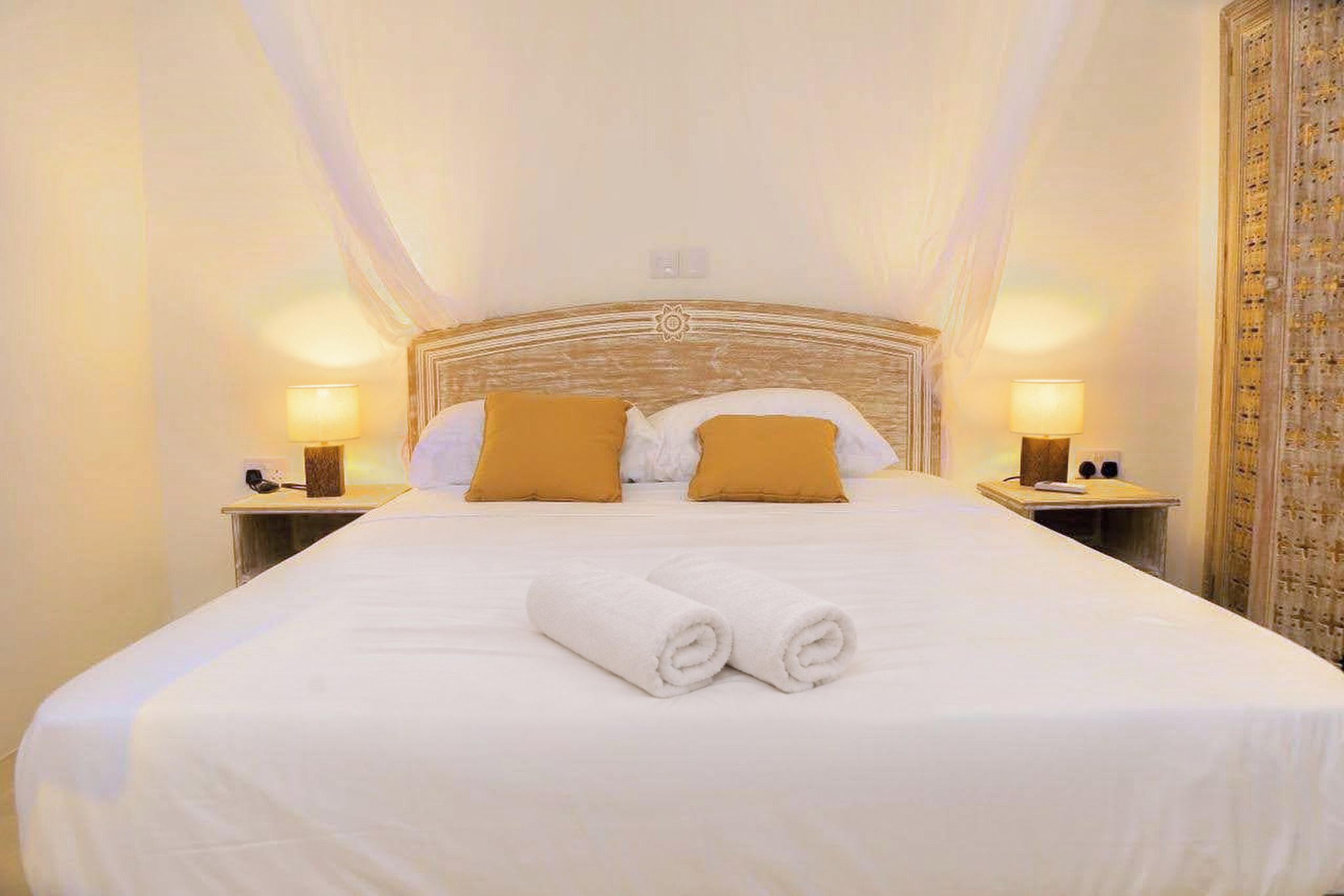 Ein Hotelzimmer mit einem großen Bett, zwei Nachttischen und einem Baldachin über dem Bett.
