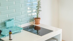 Una mesa blanca con una tableta, una planta en maceta y una cesta azul para guardar objetos.