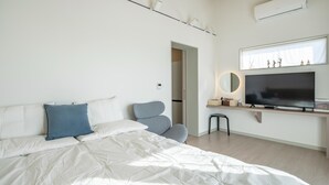 Un dormitorio moderno con cama, televisor y zona de escritorio.