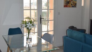 A dining area with a glass table and chairs, a blue sofa, and a door leading outside. - Appartement 3 Chambres + Terrasse de 60 m2 Au1er Étage D'une Villa à Golfe Juan (Vallauris)