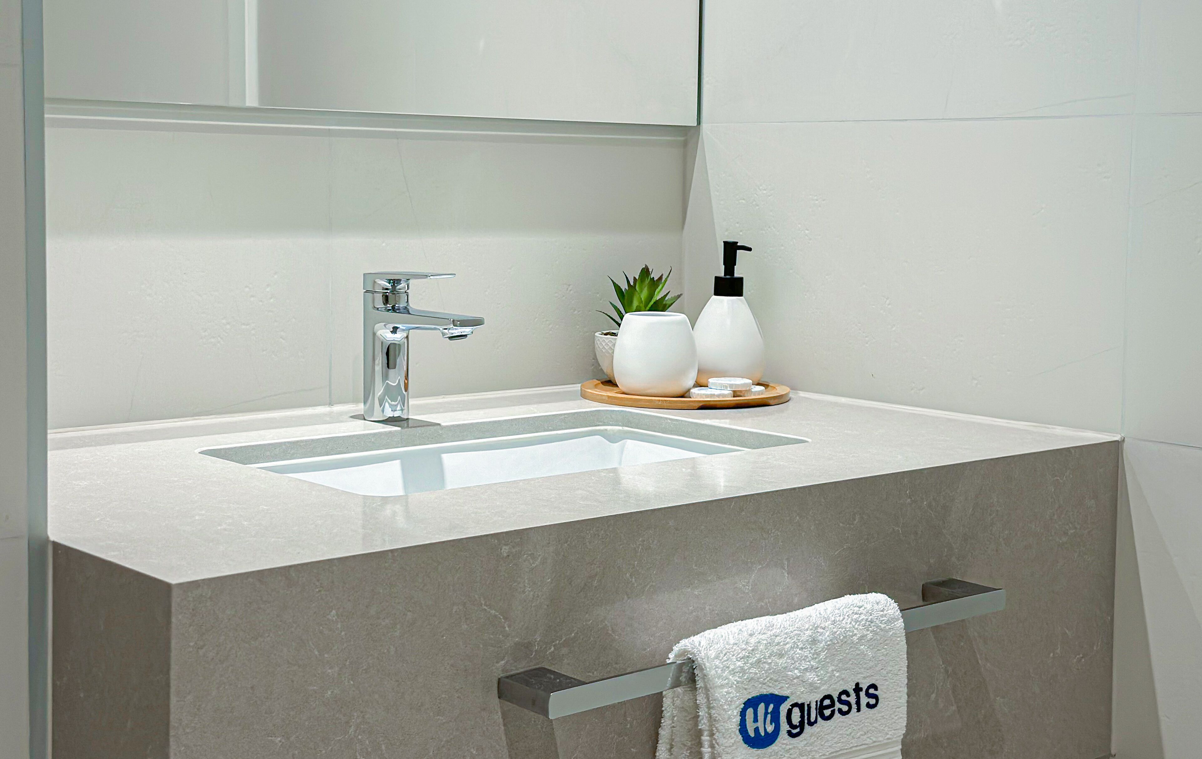 A modern bathroom with a rectangular sink, chrome faucet, and a towel rack with a towel labeled "guests".