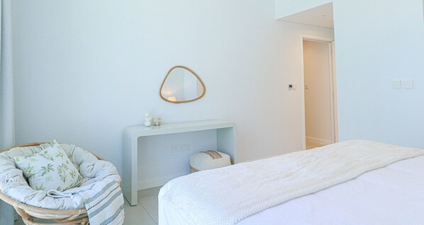 A bedroom with a bed, a bedside table, a chair, and a mirror. - HiGuests - La Vie (Dubai)