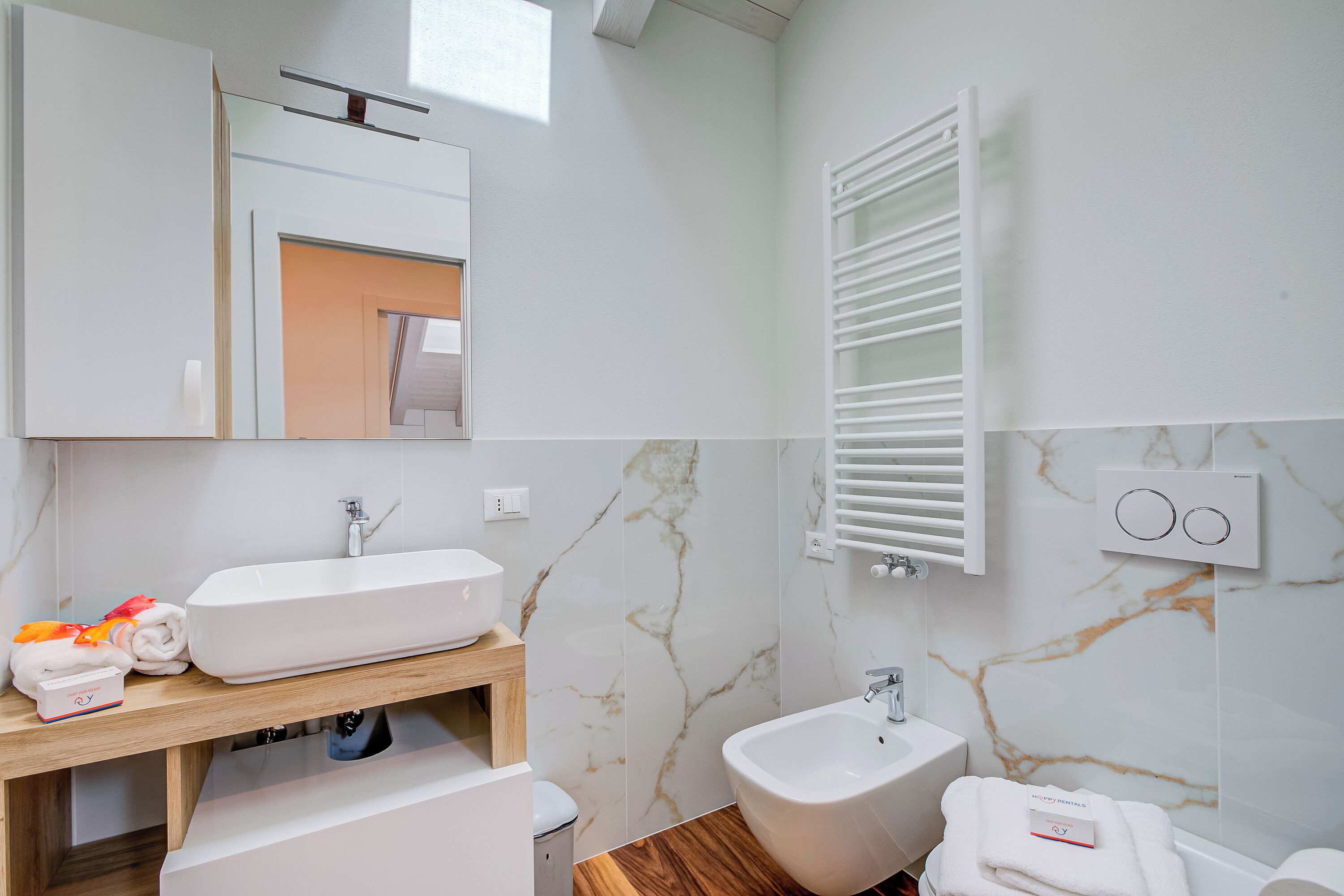 Een moderne badkamer met een witte wastafel, een toiletbril en een houten wastafelmeubel.