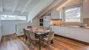 Une cuisine moderne avec un coin repas, un plancher en bois et une vue sur un paysage montagneux.