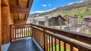 Un balcon en bois offrant une vue sur un village et des montagnes enneigées.