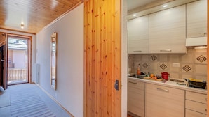 A hallway leading to a kitchen with wooden cabinets and a tiled backsplash. - Casa Ciuk (Livigno)