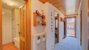 A hallway with wooden doors, a radiator, and a shelf with decorative items. - Casa Ciuk (Livigno)
