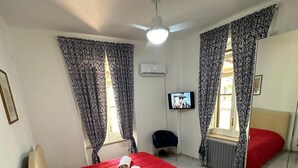 Habitación de hotel con cama, televisor, ventilador de techo y espejo.