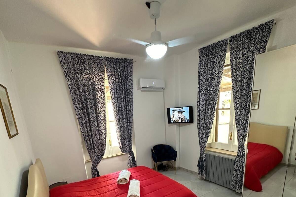 A hotel room with a bed, a TV, a ceiling fan, and a mirror.