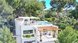 A modern multi-story house with a rooftop deck, large windows, and a swimming pool.