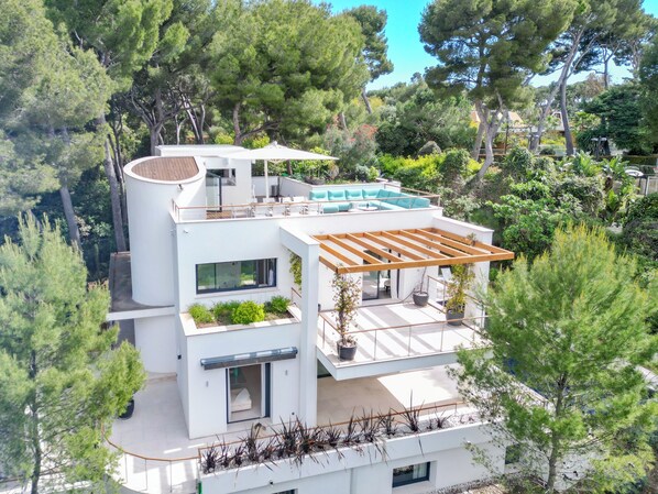 A modern multi-story house with a rooftop deck, large windows, and a swimming pool.