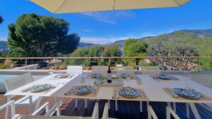An outdoor dining area with tables set for a meal, overlooking a scenic landscape.
