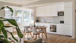 Eine moderne Küche mit weißen Schränken, einem eingebauten Backofen und einem großen Fenster.