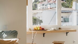 Eine Küche mit Holzausziehtisch, einem Fenster mit Blick auf Gebäude und einem Tisch mit Früchten und einer Tasse.