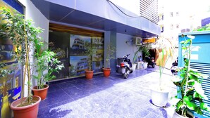 Un immeuble commercial avec une vitrine, des plantes en pot et un scooter garé à l’extérieur.