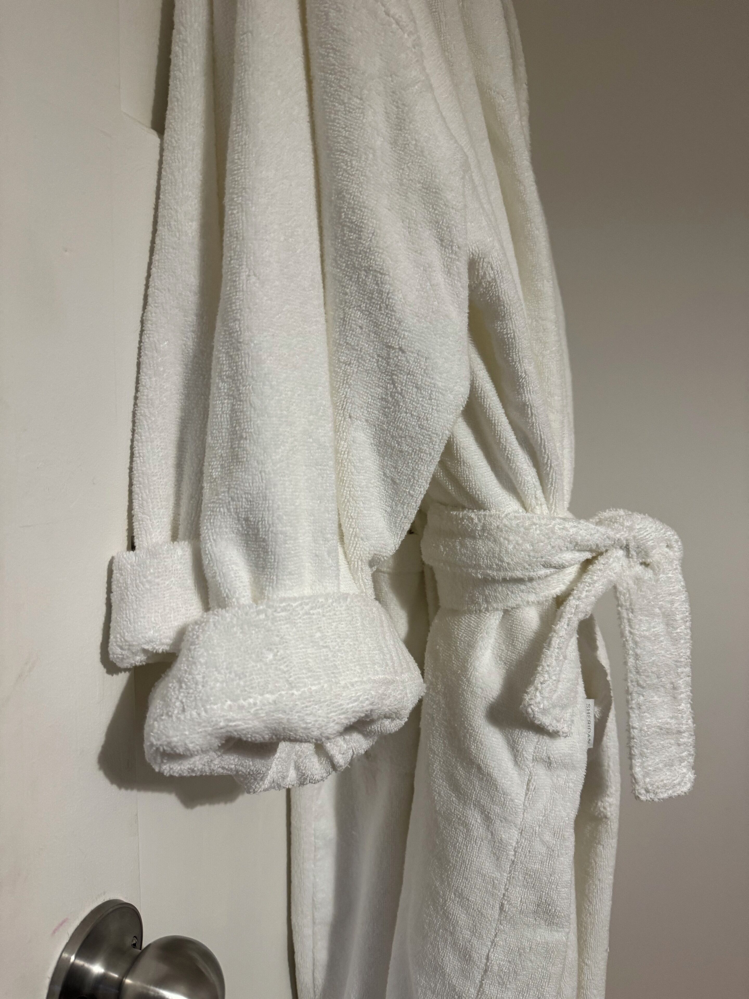 Een witte badjas hangt aan de muur.