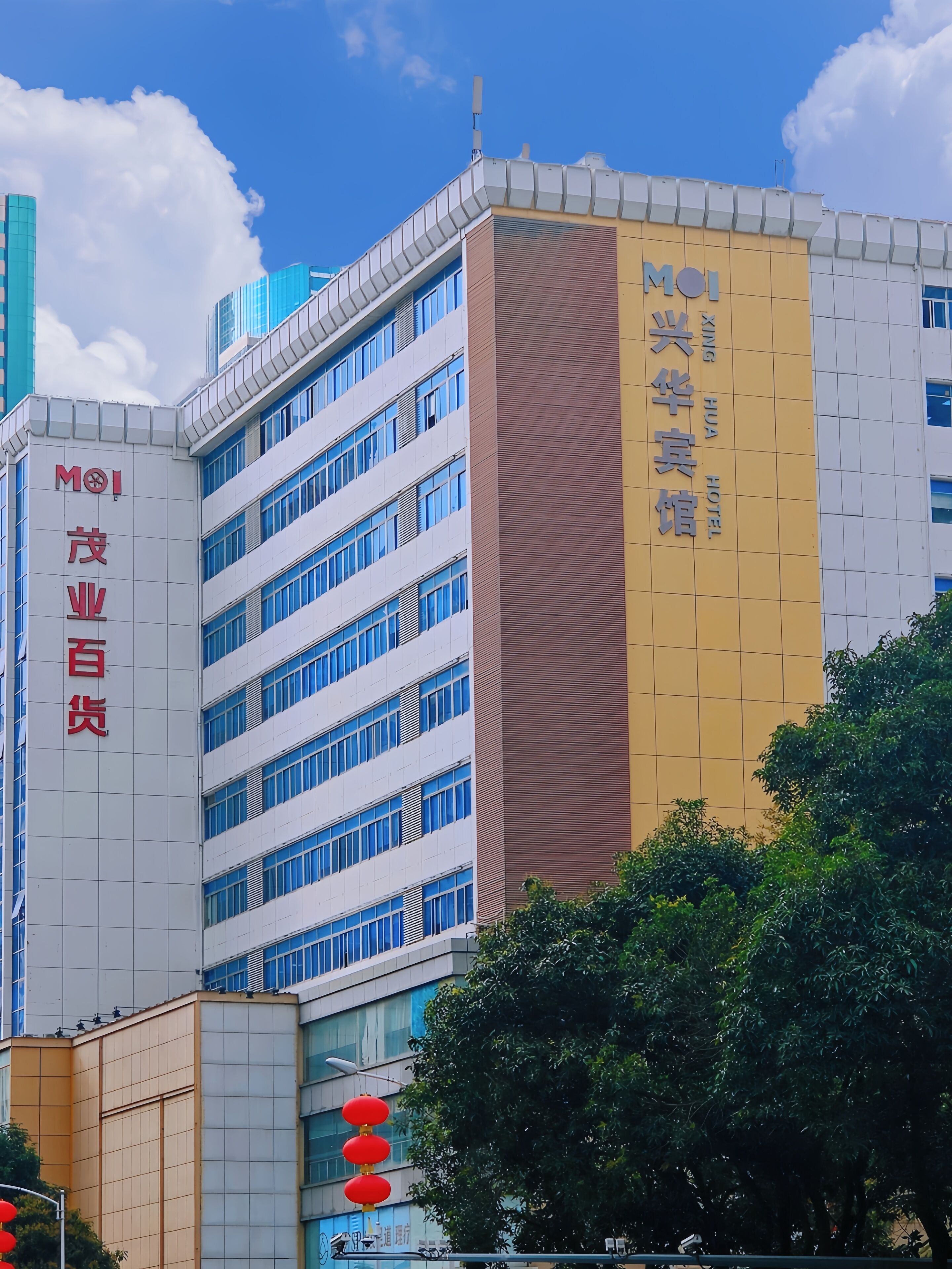 A modern building with multiple floors, including a hotel named "MOI Xinghua Hotel" on the right side.