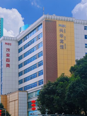 A modern building with multiple floors, including a hotel named "MOI Xinghua Hotel" on the right side. - Xinghua Hotel (Shenzhen)