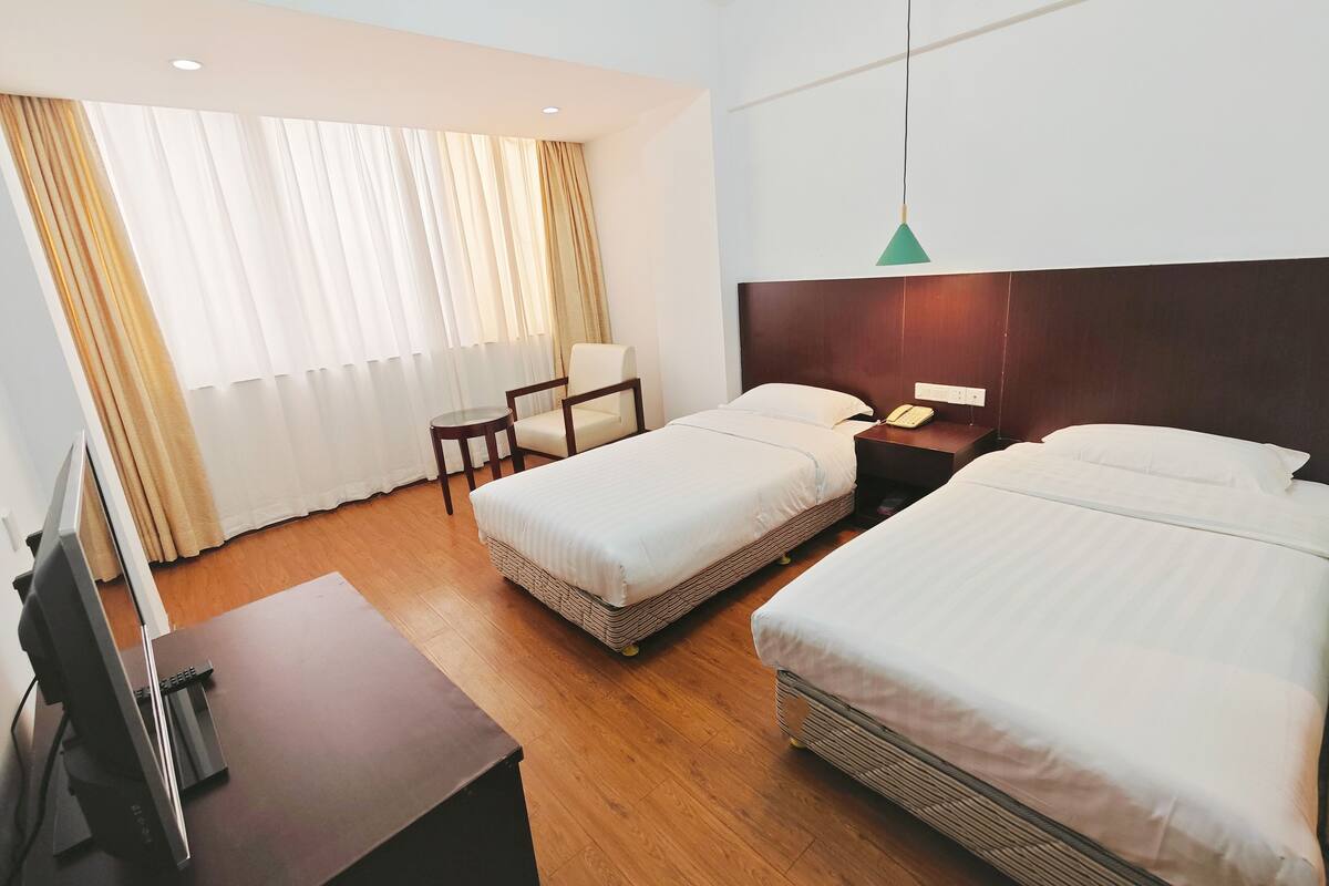 Habitación de hotel con dos camas, un escritorio, una silla y un televisor.