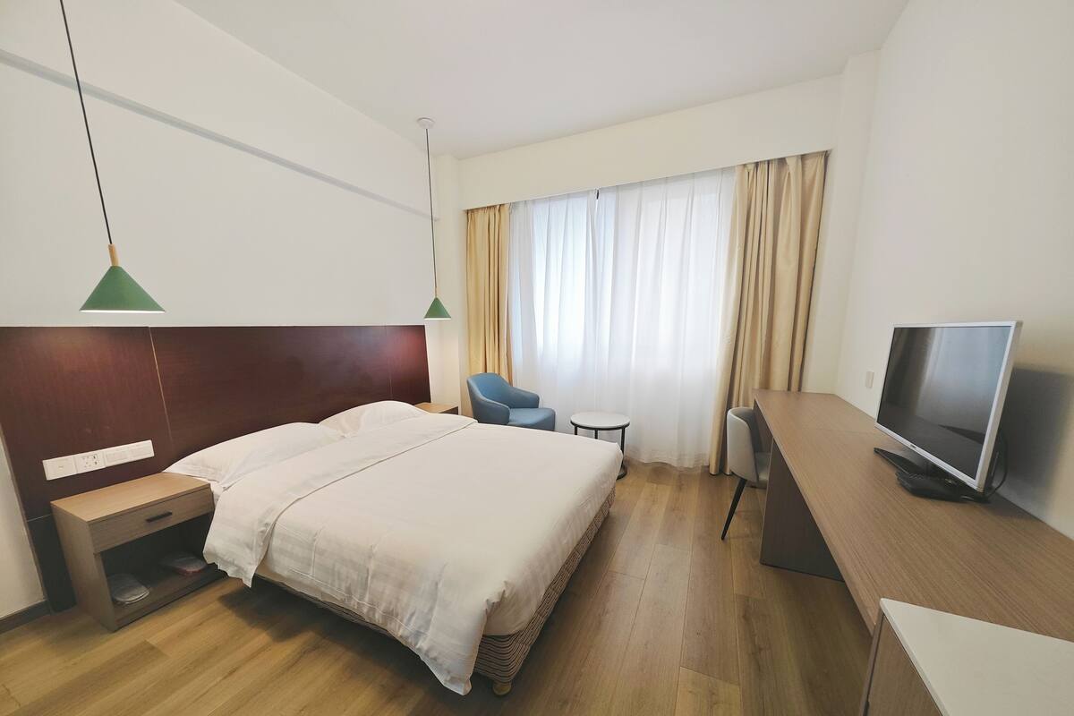 Una habitación de hotel con una cama, un escritorio, un televisor y una silla.