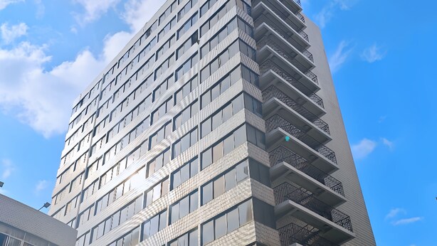 Un immeuble à plusieurs étages doté d’une architecture moderne, avec une entrée imposante et une enseigne bien visible.