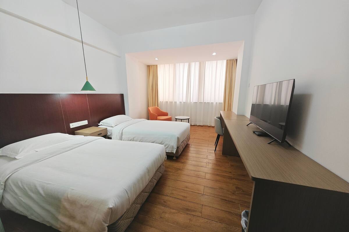 Una habitación de hotel con dos camas, un escritorio, un televisor y una silla.