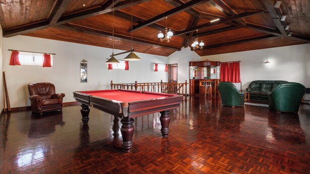 A spacious room with a pool table, leather chairs, and a billiards rack.