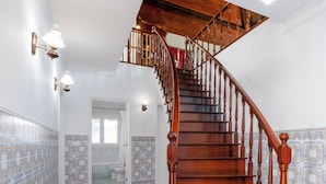 A wooden staircase with a handrail and a landing, leading to an upper floor.