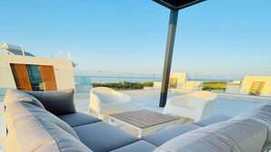 A rooftop terrace with a sofa set, a small table, and white chairs. - By the Beach Villa Natalya (Protaras)
