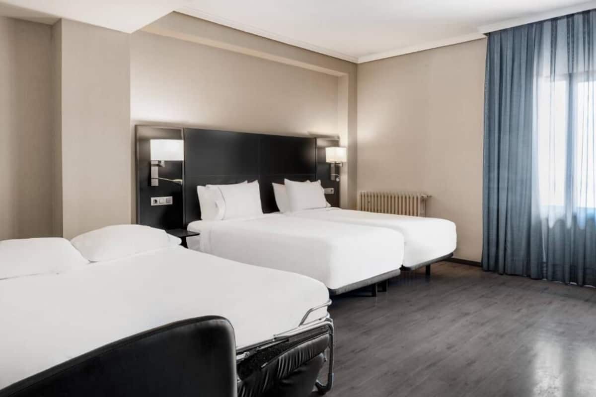 Une chambre d’hôtel avec deux lits, un bureau et une chaise.