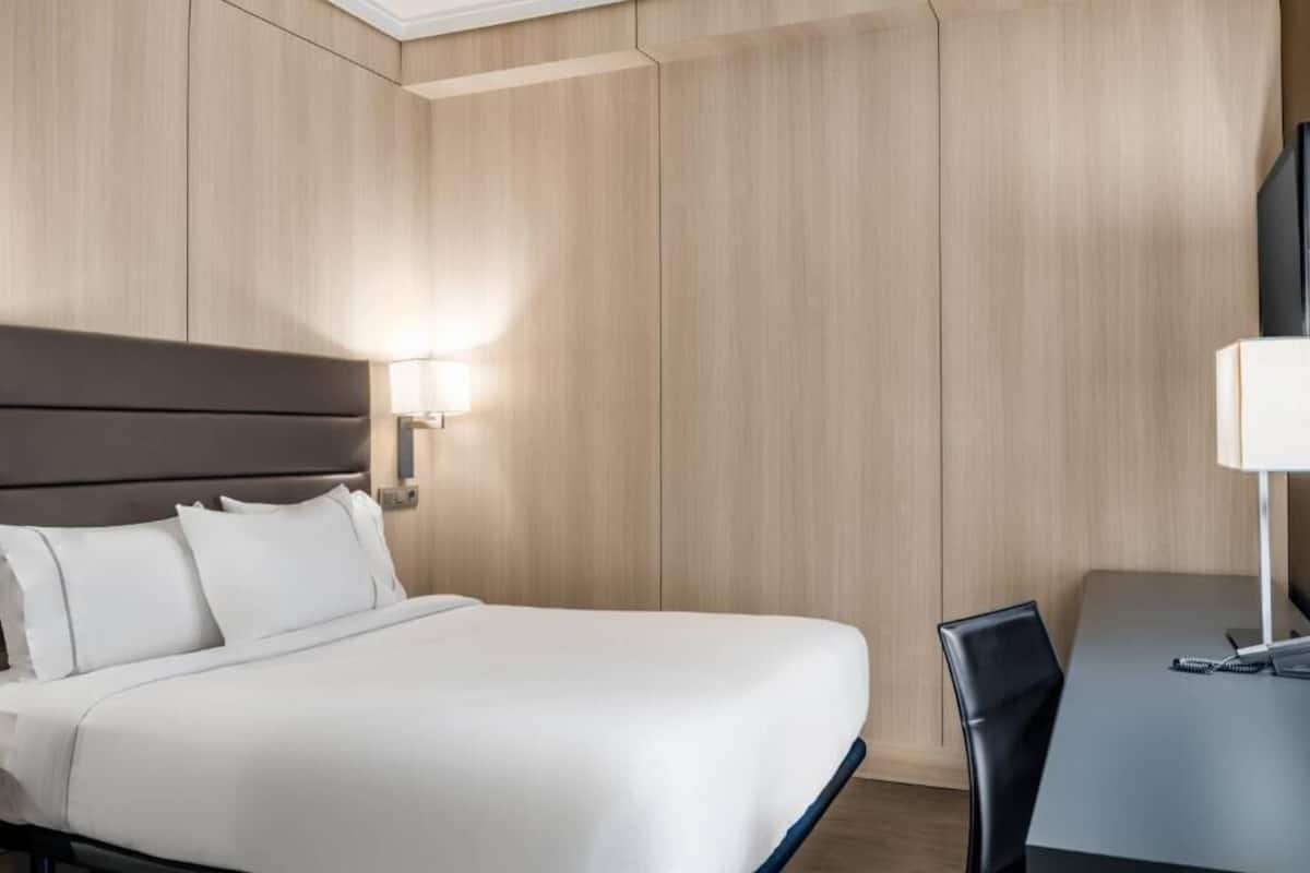 Une chambre d’hôtel avec un grand lit, un bureau et une chaise.