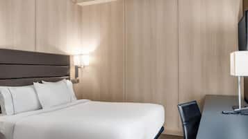 Una habitación de hotel con una cama grande, un escritorio y una silla.