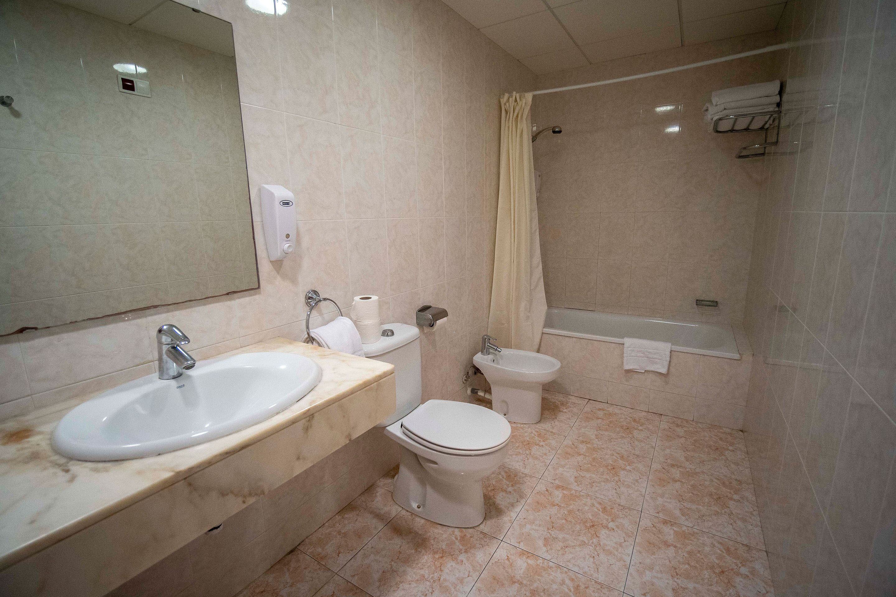 Une salle de bain moderne équipée d’un lavabo, de toilettes, d’un bidet et d’une baignoire.