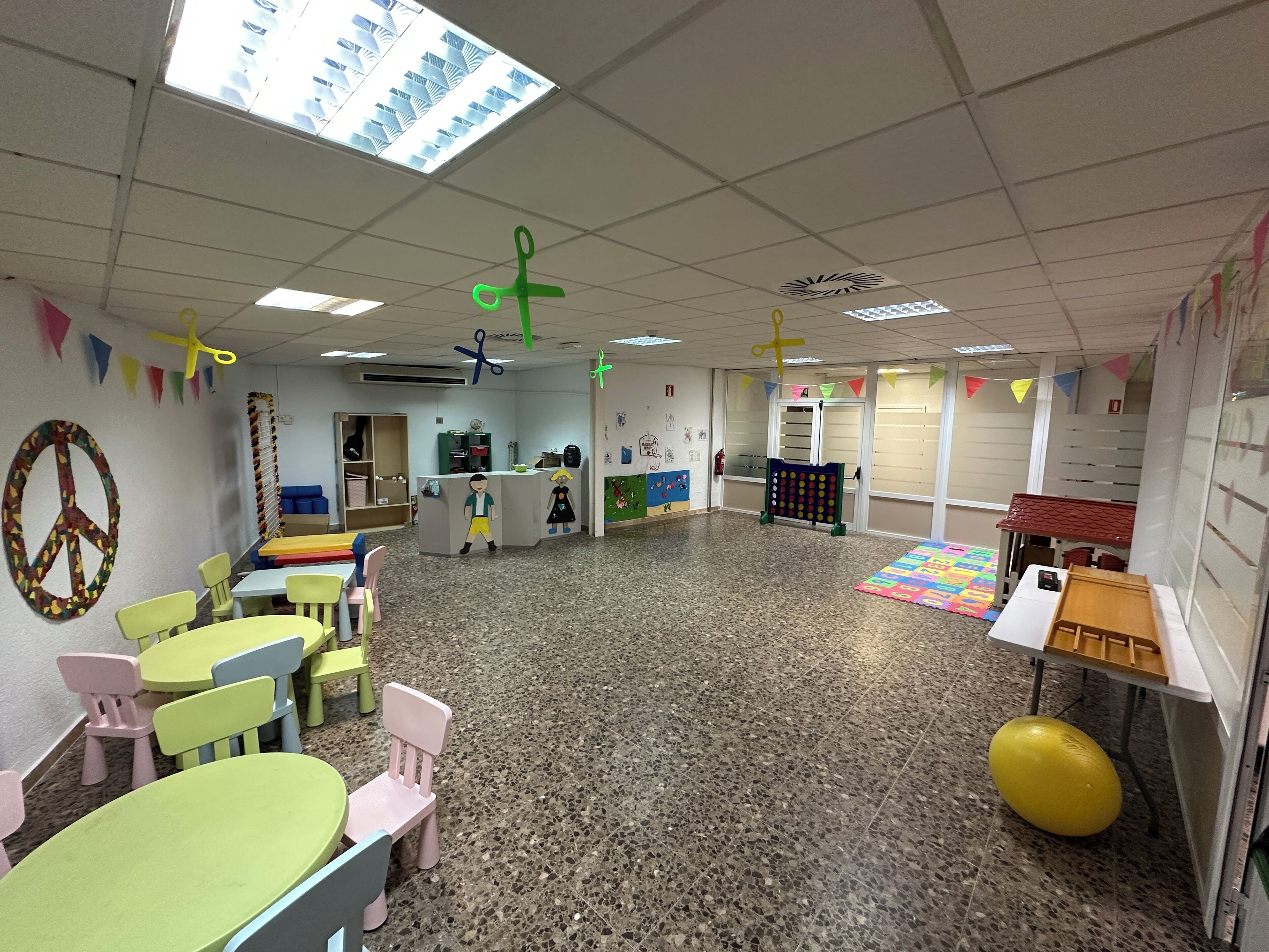 A classroom with colorful furniture, a bulletin board, and educational decorations.