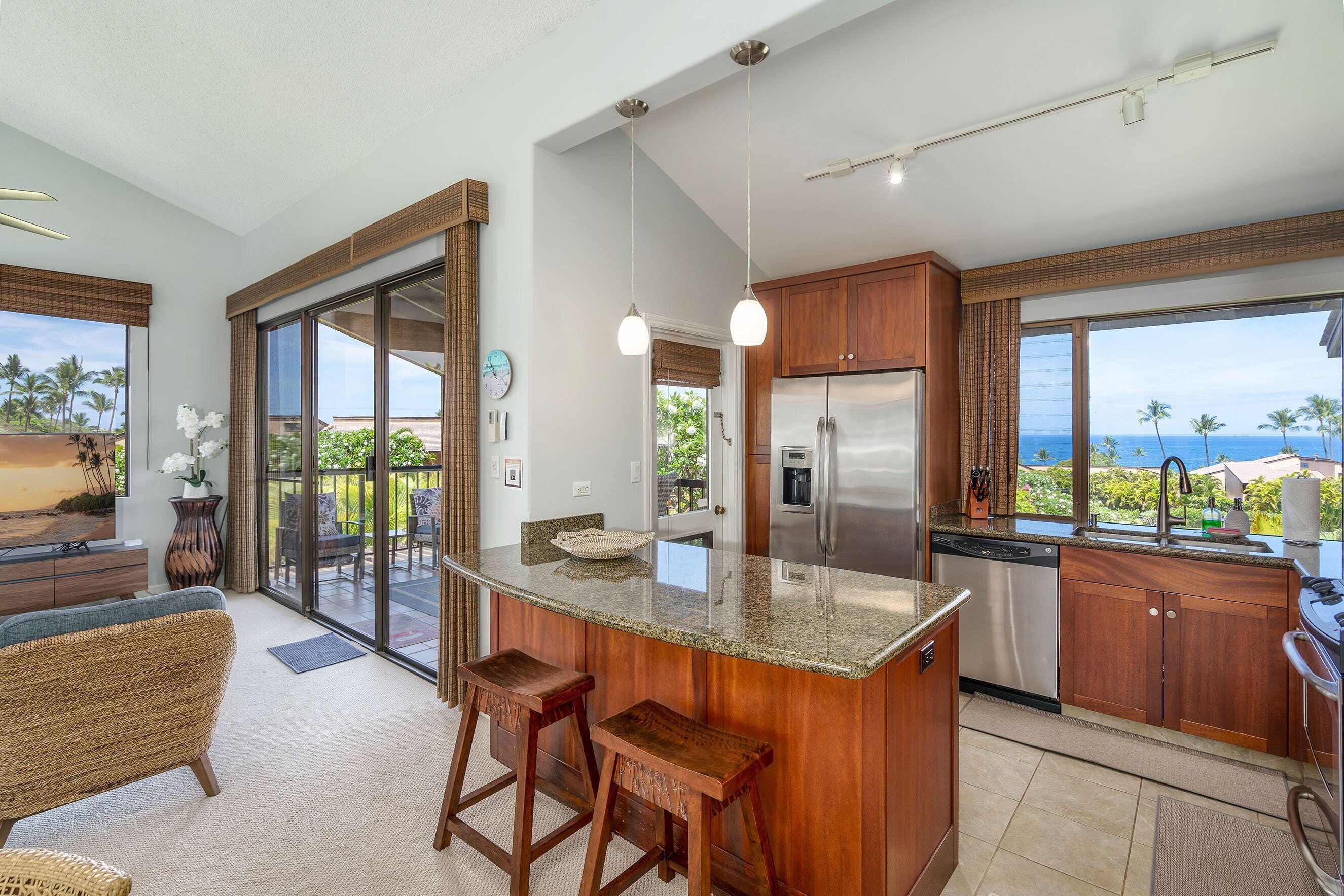 A modern kitchen with a large island, stainless steel appliances, and a view of the ocean.