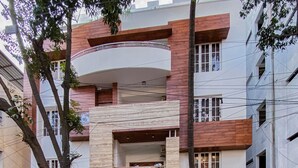 A modern multi-story building with a curved balcony, a gated entrance, and a visible sign reading "S.S. MANSION." - SS Mystic Apartotel (Bengaluru)